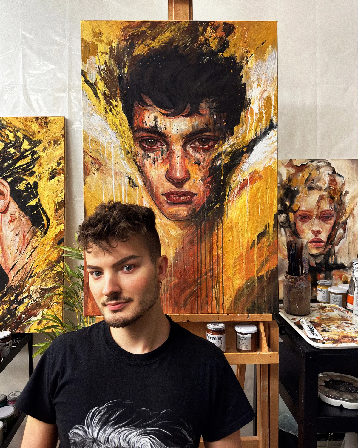Tomasz Mro in his studio with his paintings